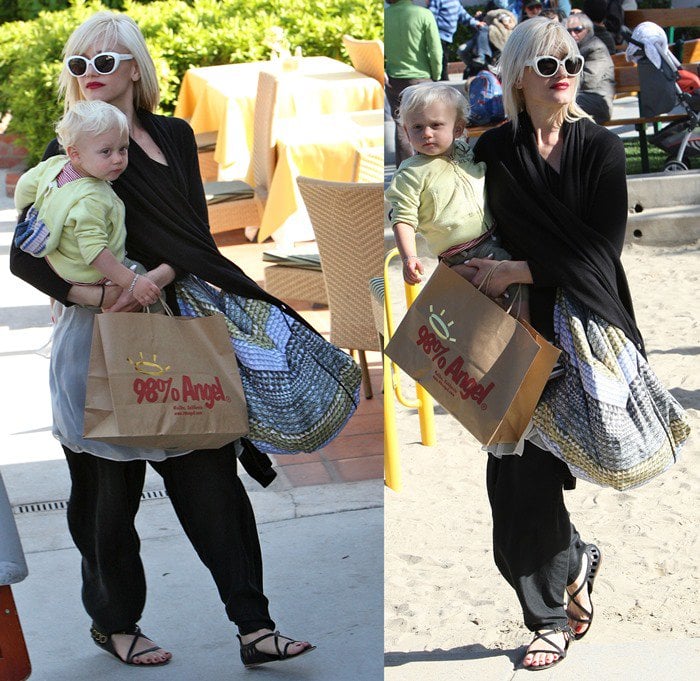 Gwen Stefani effortlessly layers a draped black cardigan over a flowy patterned skirt and relaxed harem pants, finishing the look with statement sunglasses and studded black sandals for a chic yet comfortable daytime outfit