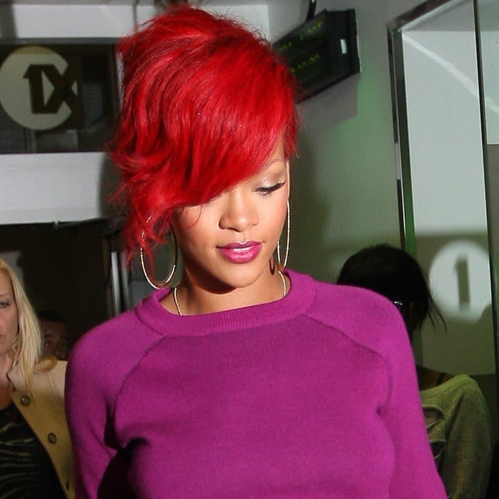 Rihanna makes a bold statement with her fiery red hair clashing vibrantly against her magenta sweater