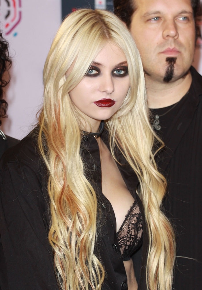 Taylor Momsen rocks her signature edgy look with dark smoky eye makeup, bold red lipstick, and long platinum blonde waves