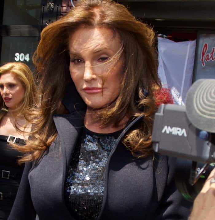 Caitlyn Jenner pairs a shimmering sequined top with a tailored navy coat, showcasing polished glamour and confident style