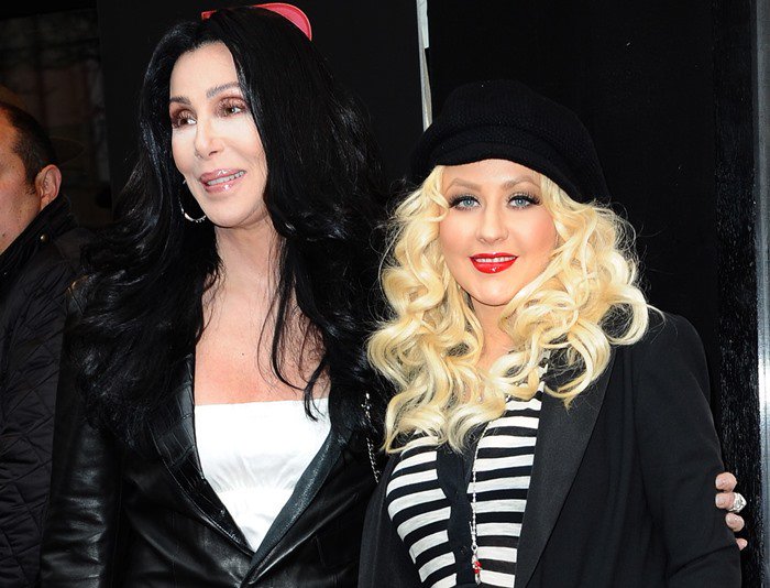 Cher radiates edgy sophistication in a leather jacket, while Christina Aguilera channels Parisian chic with her striped top and newsboy cap at the 'Burlesque' Paris photocall