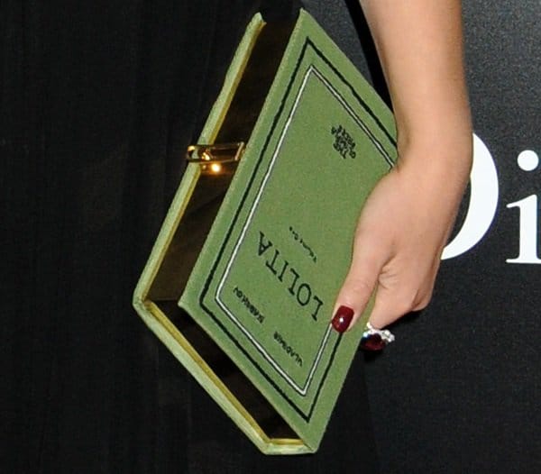 Natalie Portman carries a whimsical Olympia Le-Tan “Lolita” book-clutch — a handmade literary-themed accessory that adds an intellectual twist to her Dior ensemble at the Black Swan premiere
