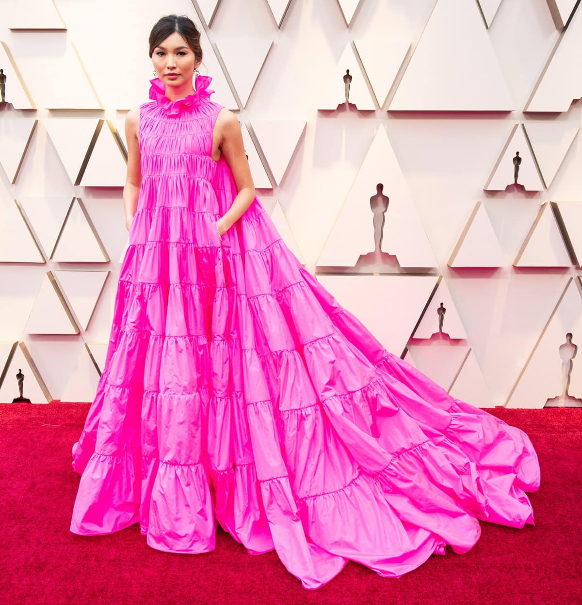 Gemma Chan exudes elegance at the 2019 Oscars in a dramatic Valentino fuchsia gown, perfectly paired with Jimmy Choo heels for a regal red carpet moment