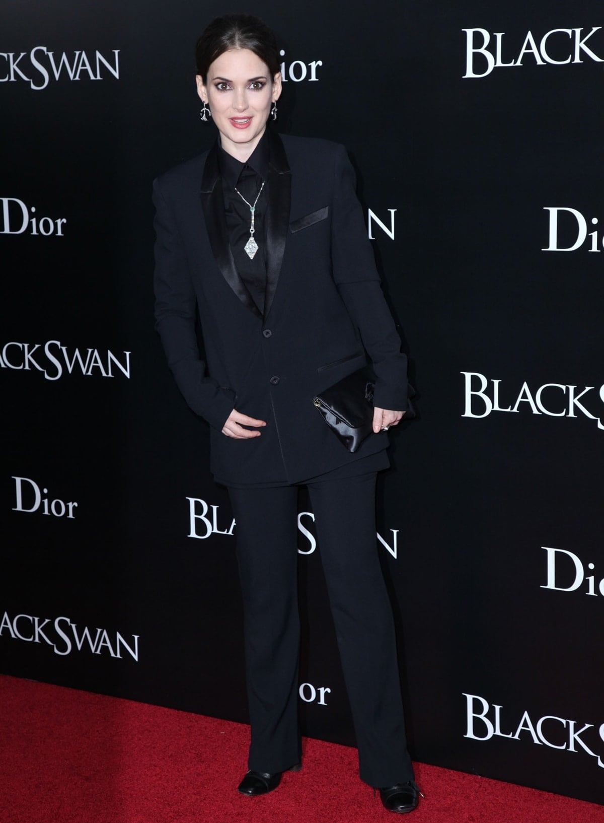 Winona Ryder channels modern elegance in a black Givenchy Resort 2011 suit paired with Stephen Russell jewelry and a Lanvin Ouloulette satin brooch clutch at the Black Swan premiere in New York on November 30, 2010