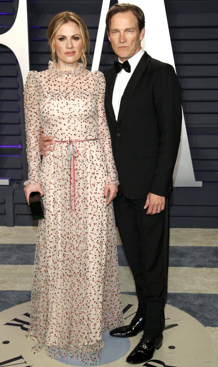 Anna Paquin looked radiant in a sheer floral Monique Lhuillier gown, styled with a Lala Léxa clutch and strappy Schutz heels, as she posed with husband Stephen Moyer at the 2019 Vanity Fair Oscar Party