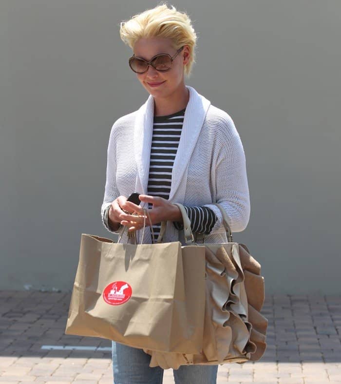 Katherine Heigl keeps it effortlessly chic in a striped top layered with a cozy white knit cardigan, paired with classic blue jeans and oversized sunglasses for a relaxed shopping day