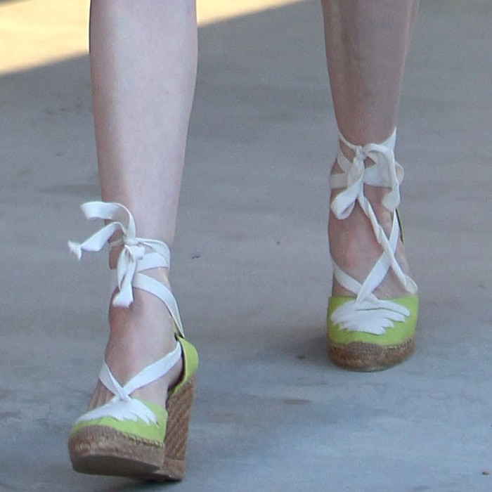 A closer look at Dita's Christian Louboutin espadrille wedges, featuring vibrant lime green canvas, delicate white detailing, and chic ribbon ankle ties for a retro-feminine touch
