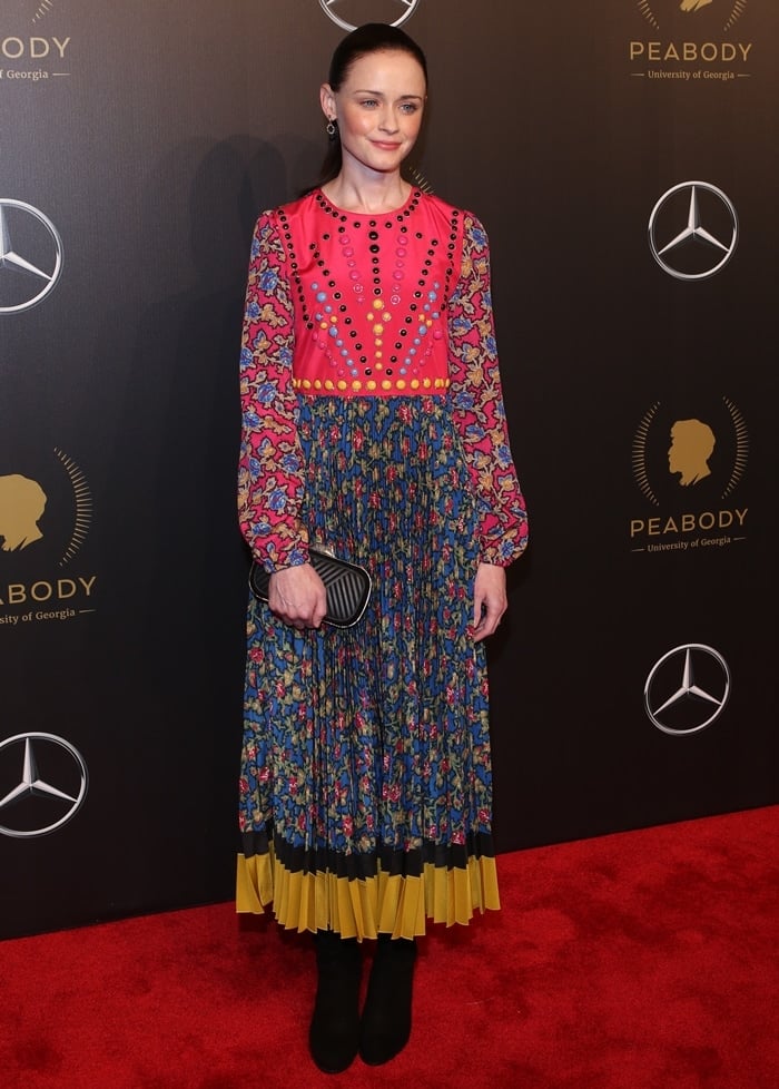 Alexis Bledel paired a richly patterned Valentino midi dress with sleek black suede ankle boots at the Peabody Awards on May 19, 2018, balancing the look’s vibrant embroidery and pleated hem with understated footwear in New York City