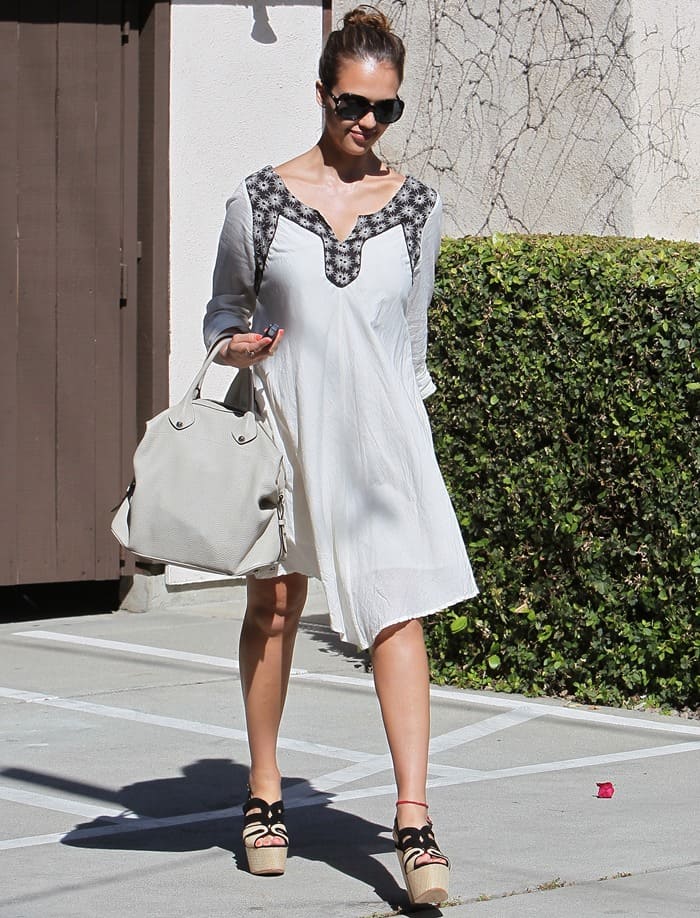 Jessica Alba arrived at Poko Event Production Studios in Westwood on April 28, 2011, wearing a breezy embroidered white dress styled with towering Nine West “Pawla” raffia platforms, oversized Versace sunglasses, and her softly structured Loewe “May” bag