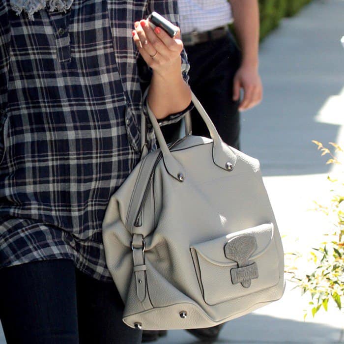 A close-up of Jessica Alba carrying the softly structured Loewe “May” bag in textured ivory leather, featuring the signature flap tab detail that defined the brand’s Stuart Vevers era