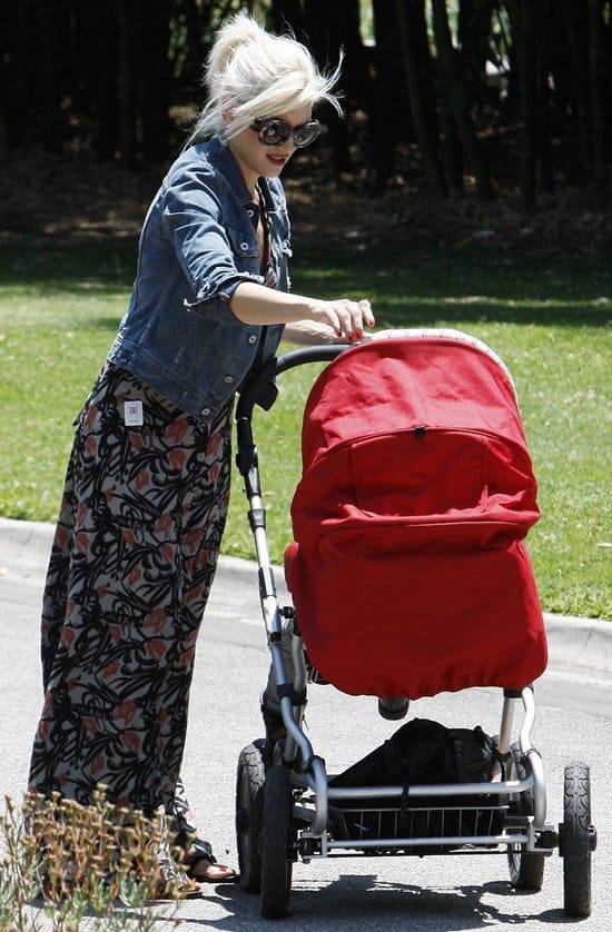 Gwen Stefani looking effortlessly chic in a Winter Kate Passenger halter neck maxi dress, AG Robyn denim jacket, Prada SPR 27NS Baroque sunglasses, and flat sandals for a stylish yet relaxed summer look