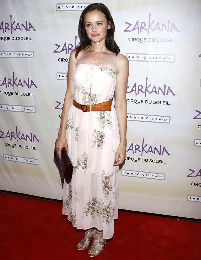 Alexis Bledel graces the Zarkana by Cirque du Soleil premiere at Radio City with effortless charm, donning a breezy floral print Twelfth Street by Cynthia Vincent maxi dress that whispers of summer nights, cinched with a tan belt, and paired with strappy metallic heels that add a subtle touch of glamour