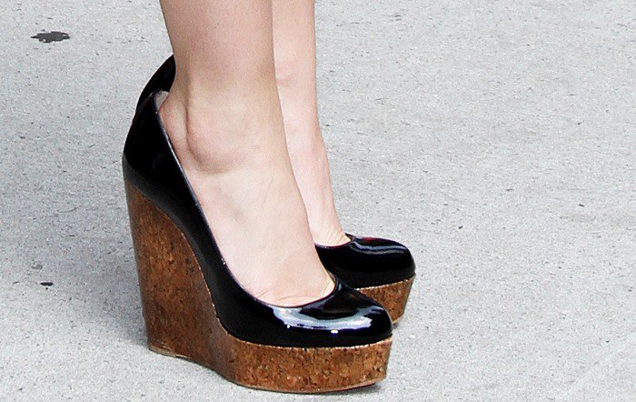 Emma Watson's black patent Christian Louboutin Coroclic wedge pumps appear noticeably too large, with a visible gap at the heel and excess space around her feet