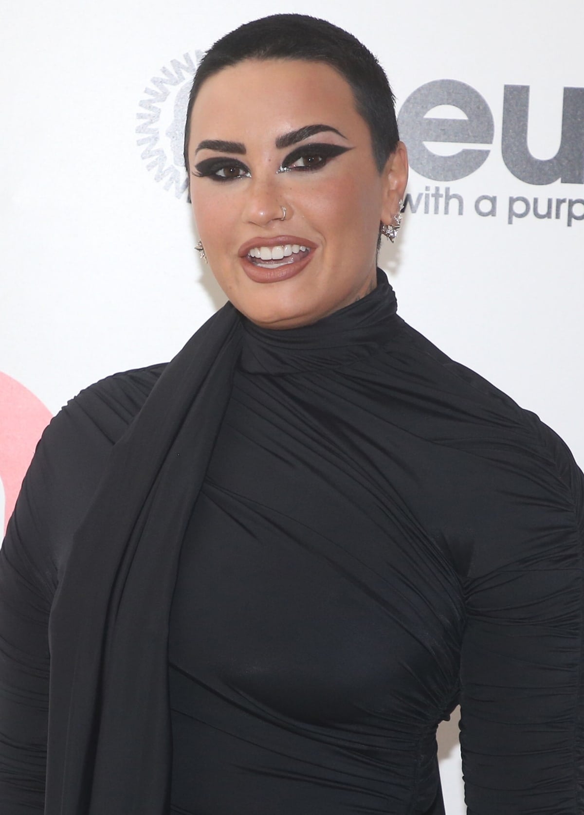 Demi Lovato stuns in a sleek black Balenciaga gown with bold smokey eye makeup, glossy nude lips, and a buzz cut at the Elton John AIDS Foundation Academy Awards Viewing Party