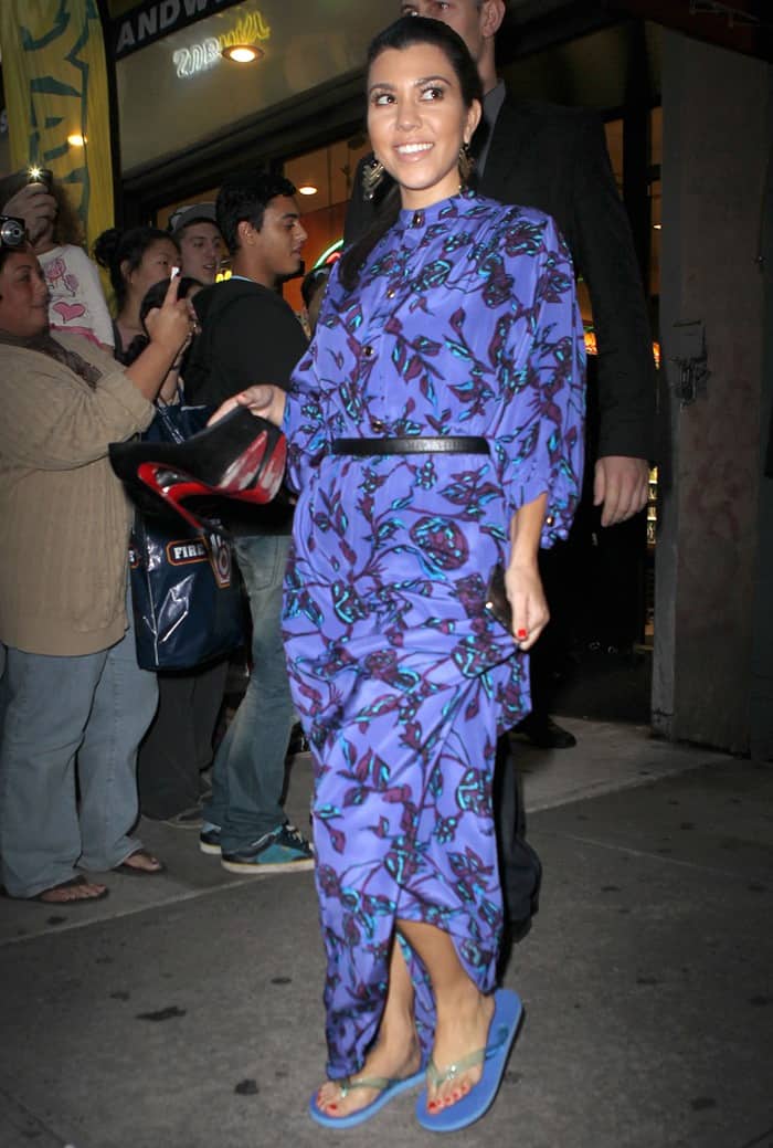 Kourtney Kardashian was spotted in New York City pairing a purple floral Sunner dress with blue flip flops, casually holding her Christian Louboutin heels as she embraced a more laid-back vibe for the evening