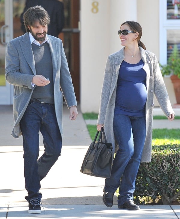 Ben Affleck walks beside a visibly pregnant Jennifer Garner, who wears a navy top, maternity jeans, and black sneakers, both styled in cozy gray coats for a coordinated casual look