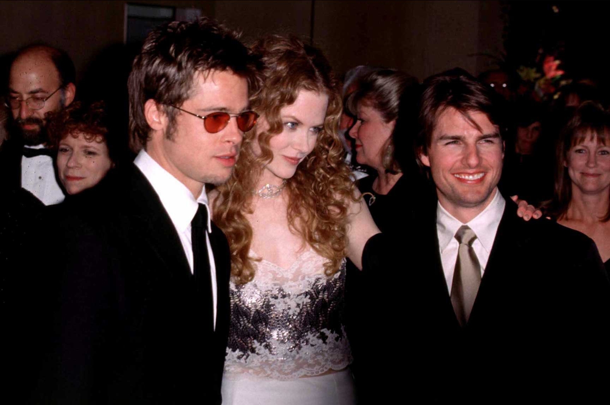 Brad Pitt and Nicole Kidman tower over a smiling Tom Cruise, highlighting the noticeable height difference as all three pose in classic black-tie attire at a red carpet event