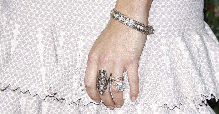 Layered cocktail rings and vintage-inspired diamond jewelry added extra sparkle and texture against the understated blush-toned fabric