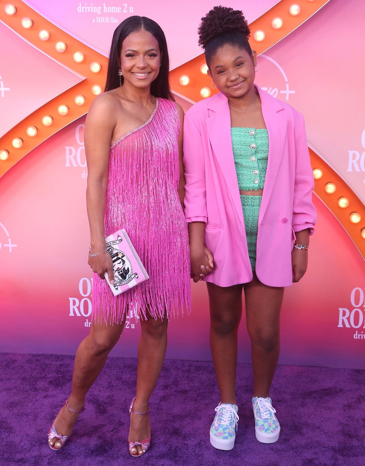 Christina Milian dazzled in a pink sequined fringe mini dress by Paola Estefania, styled with metallic strappy heels and a whimsical Charlotte Olympia book clutch, while Violet Madison Nash complemented the purple-carpet moment in a chic mint-green tweed set layered under an oversized pink blazer and finished with pastel platform sneakers