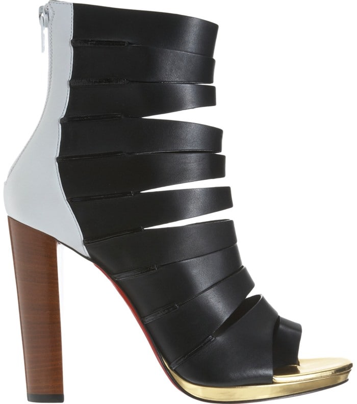 Christian Louboutin’s Decoupata ankle boot stuns with sculptural leather cutouts, a towering wooden heel, and the brand’s signature red sole grounded by a gleaming gold platform