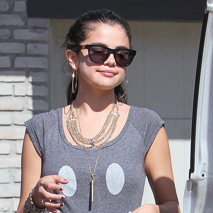 Selena Gomez accessorizes her casual Sauce smiley-print dress with Westward Leaning sunglasses, layered Stella Dot necklaces, Forever 21 chain jewelry, and oversized hoop earrings