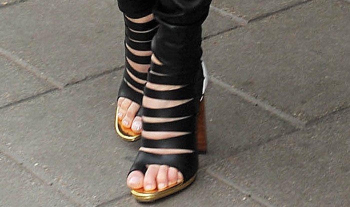 Charlize Theron steps out in bold Christian Louboutin platform sandals, where cage-like wraparound straps meet sky-high heels and a flash of gold at the sole for an edgy, statement finish