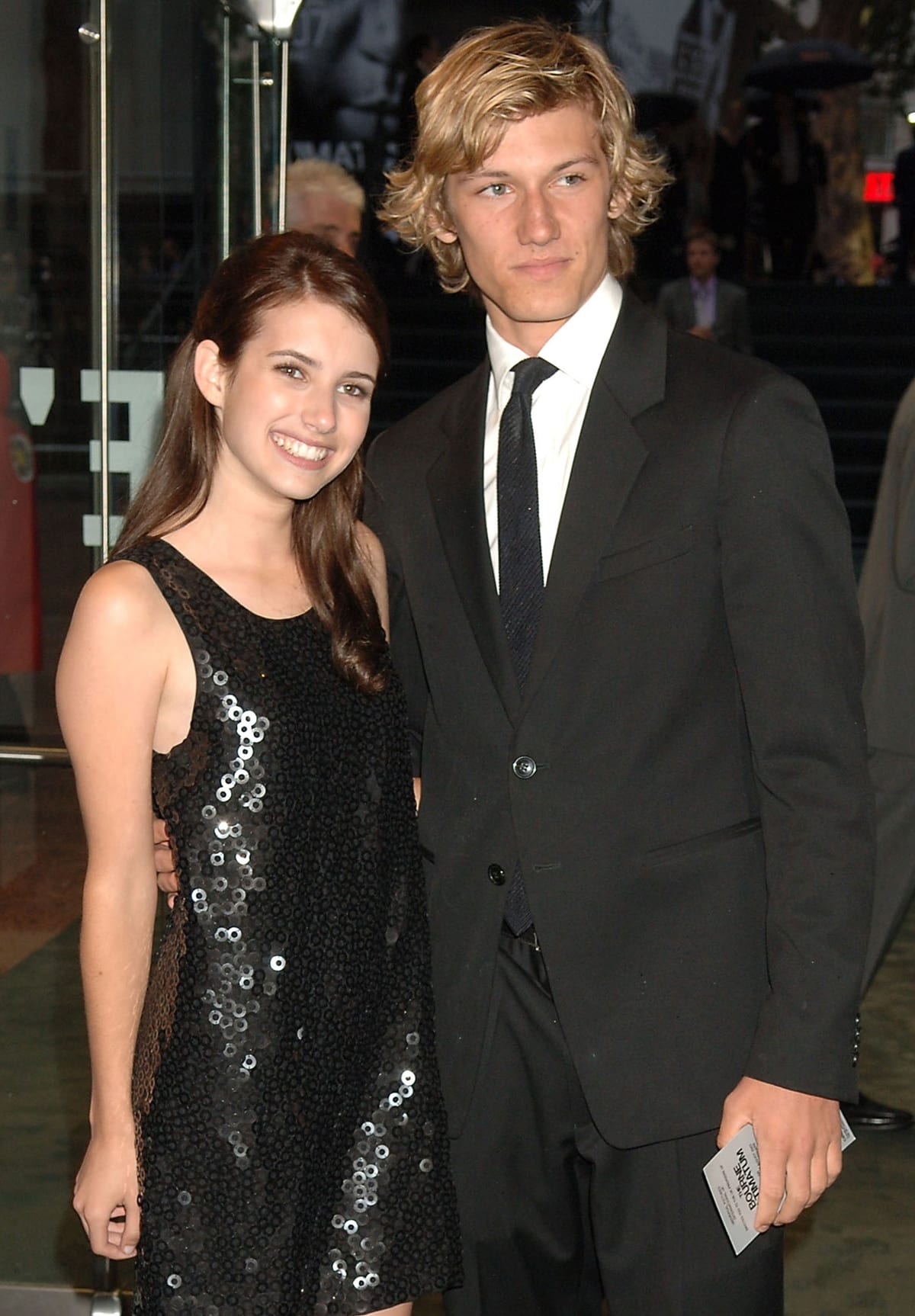 Emma Roberts, in a sequined black dress, poses with her then-boyfriend Alex Pettyfer, dapper in a classic suit, after the two met on the set of Wild Child in 2007