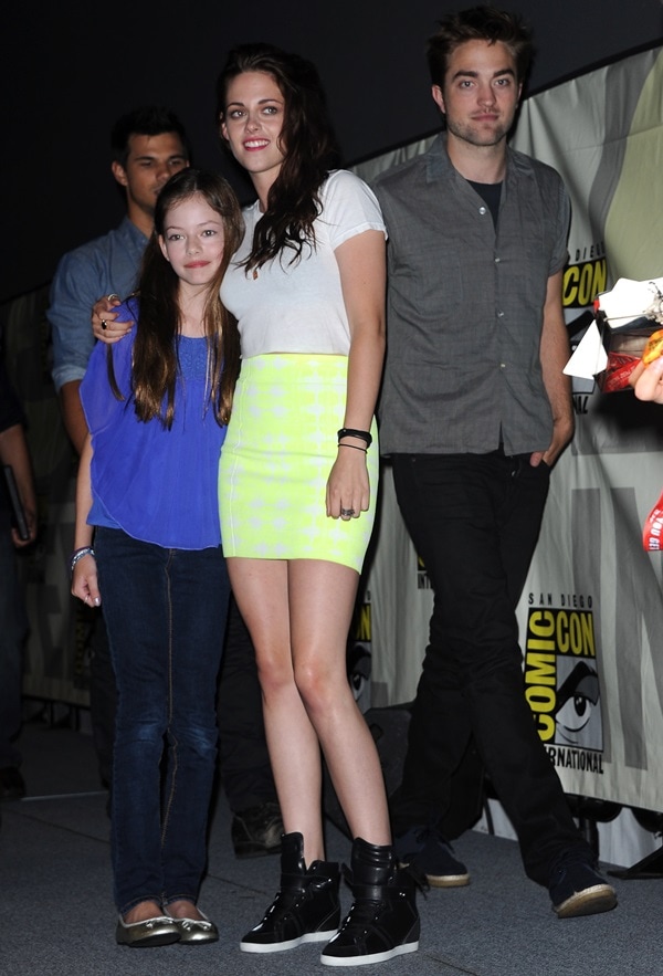Kristen Stewart balances casual edge and early-2010s cool in a Fluxus crop top, a neon-yellow BCBG miniskirt, and black hidden-wedge sneakers