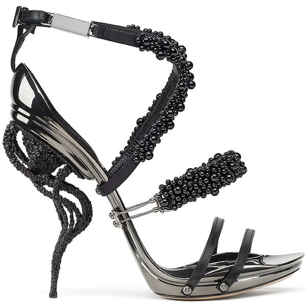 Gianluca Tamburini Beluga Gianluca Tamburini's Beluga sandal stuns with modular black beaded straps, a sleek metallic sole, and an intricately sculpted heel—blending avant-garde artistry with high-tech automotive influence