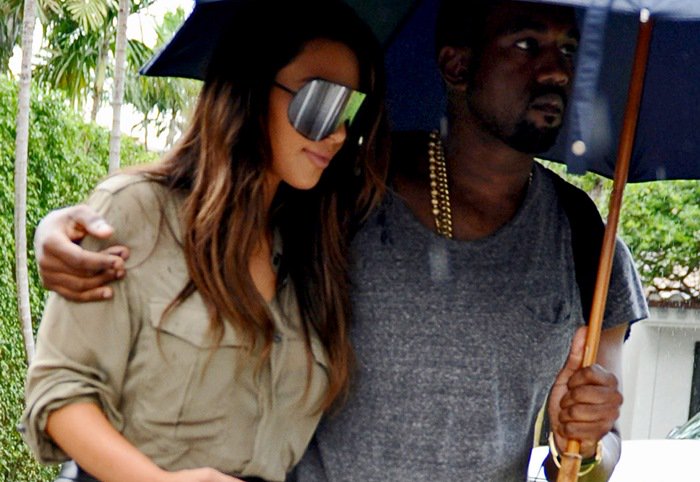 Kim Kardashian and Kanye West cuddled together under an umbrella