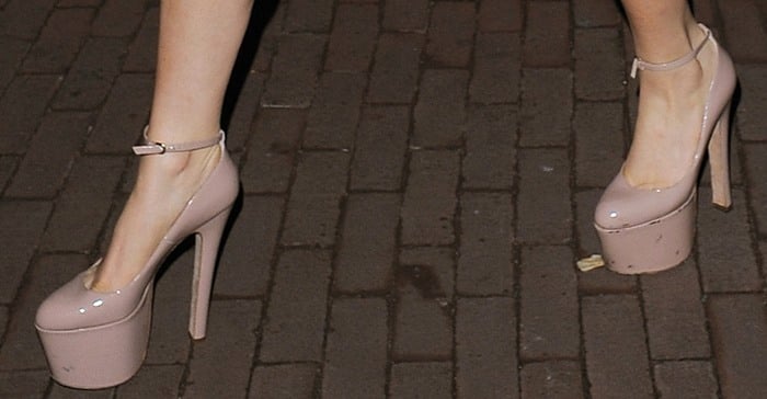 Lady Gaga’s nude patent pumps feature exaggerated platform soles, slender ankle straps, and towering stiletto heels