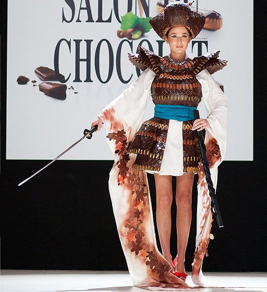The Chocolate Dress Fashion Show Yoake San embodies strength and style in chocolate armor, featuring a meticulously crafted headdress, showcasing the versatility of chocolate as a medium