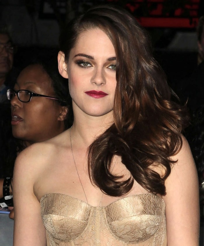 Kristen Stewart wore her long auburn hair swept dramatically to one side in loose, glossy waves, pairing the elegant style with smoky eye makeup and deep berry lipstick for a sultry red-carpet finish