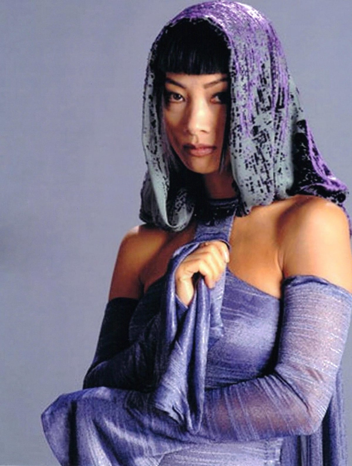 Bai Ling wears a shimmering off-the-shoulder violet gown with sheer, textured sleeves and a matching hooded veil as Senator Bana Breemu in Star Wars: Episode III – Revenge of the Sith (2005)
