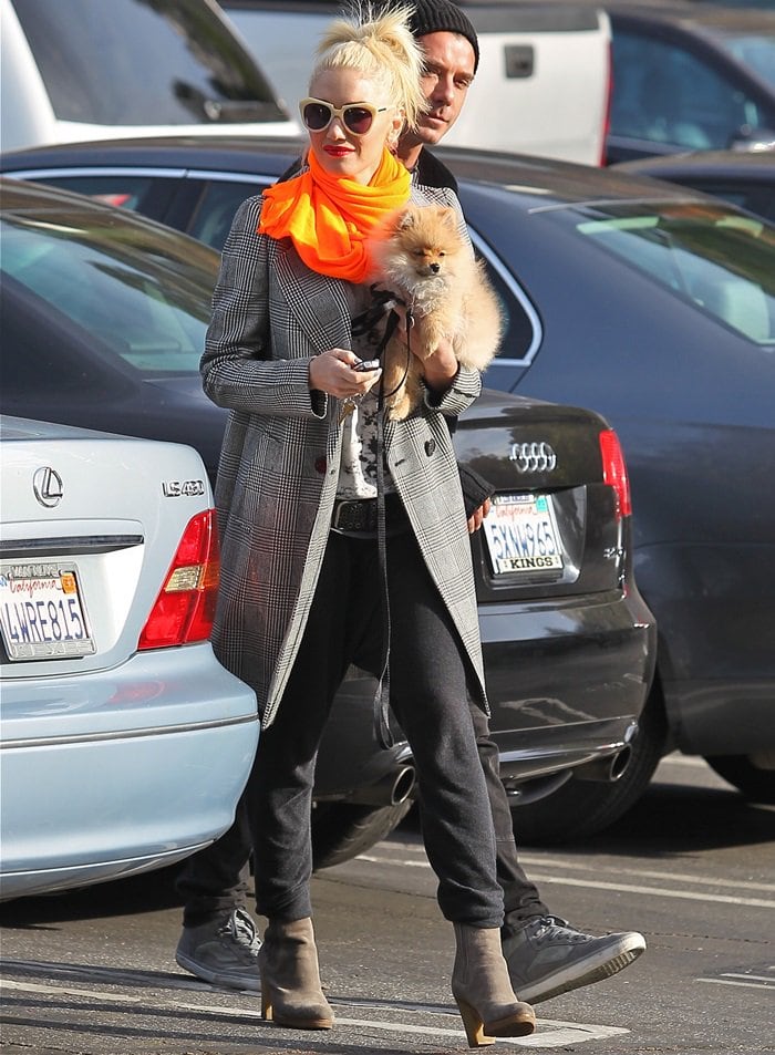 Gwen Stefani grounded her neon scarf moment with taupe suede ankle boots, using a neutral heel to anchor the sharp contrast between tailored layers and high-impact color