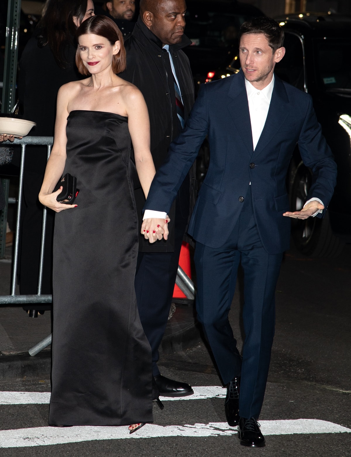 Kate Mara stuns in a strapless black gown, paired with strappy sandals, as she walks hand-in-hand with her husband Jamie Bell, who looks sharp in a classic navy suit