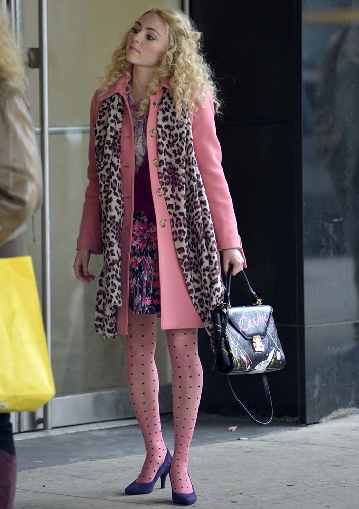 AnnaSophia Robb finishes her bold '80s-inspired outfit with classic pointed-toe purple suede pumps that add a vibrant pop of color and complement her playful polka-dot tights