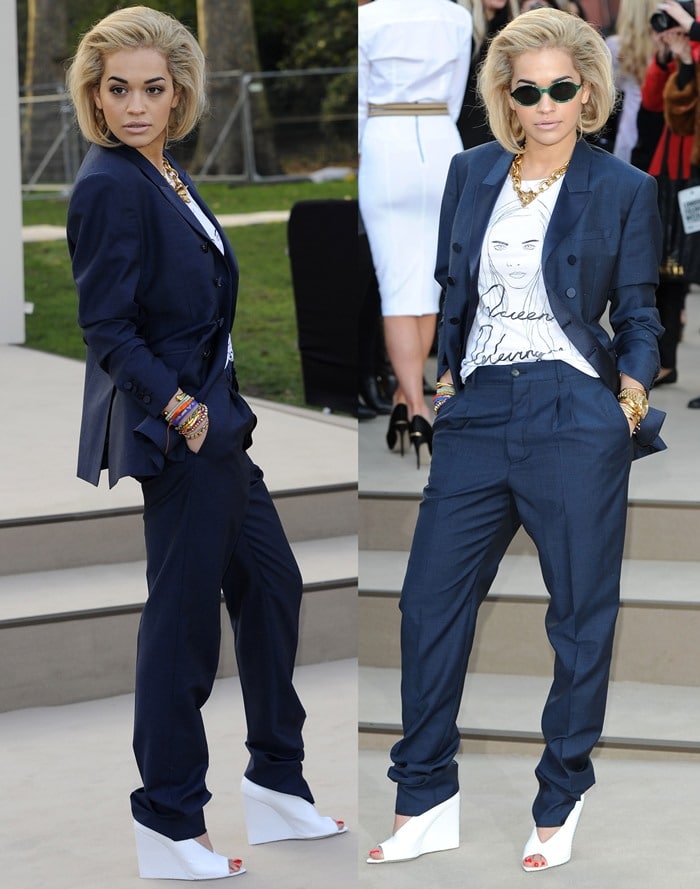 Rita Ora pairs crisp white Burberry Prorsum wedge sandals with a navy tailored suit and a graphic tee, blending androgynous edge with playful statement accessories at London Fashion Week