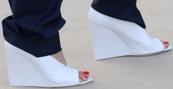 Rita Ora shows off a bold red pedicure in textured white peep-toe wedge sandals from Burberry Prorsum, featuring a sculptural silhouette and sleek, modern finish