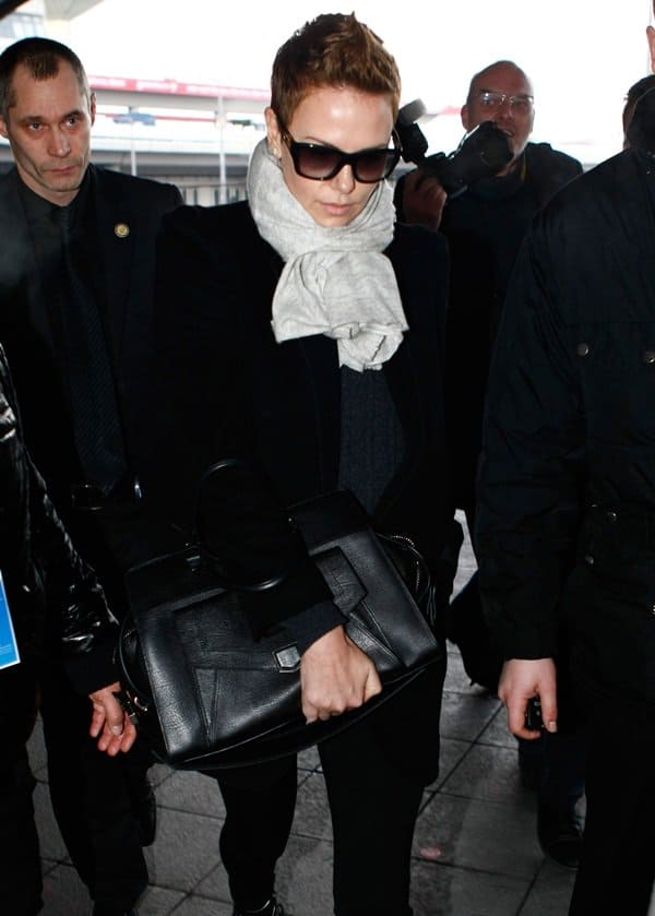 Fashion-forward: Charlize Theron accessorizes with a chic Proenza Schouler PS13 geometric tote, a testament to her impeccable taste in luxury handbags