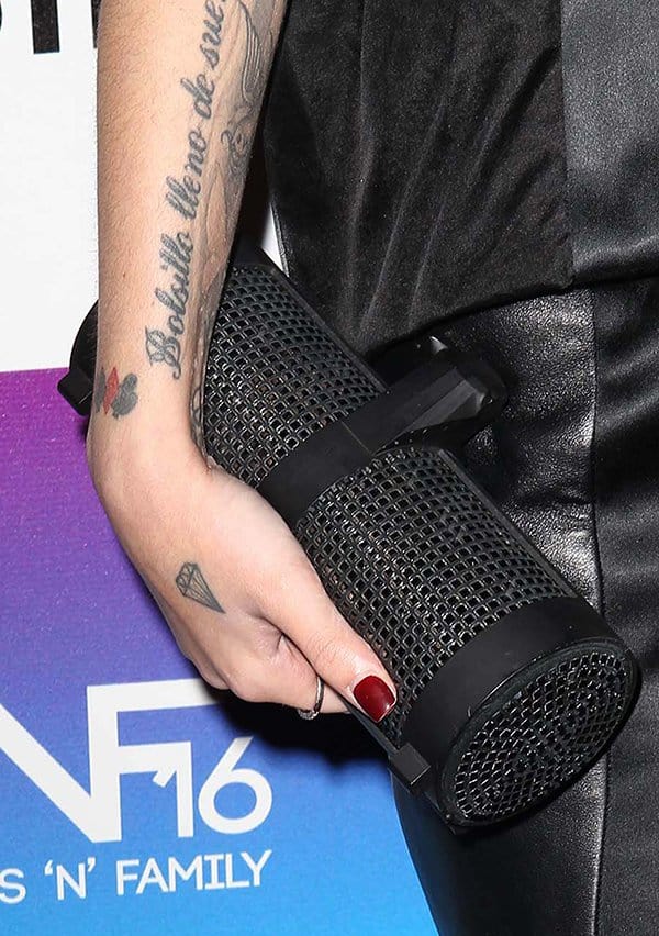 Cher Lloyd’s cylindrical black studded clutch brings a fierce, avant-garde twist to her structured leather ensemble
