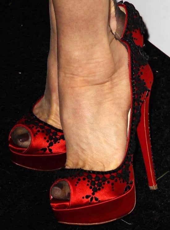A close-up of Dita Von Teese's striking Christian Louboutin ‘Torero’ pumps showcasing intricate black lace details against bold red satin
