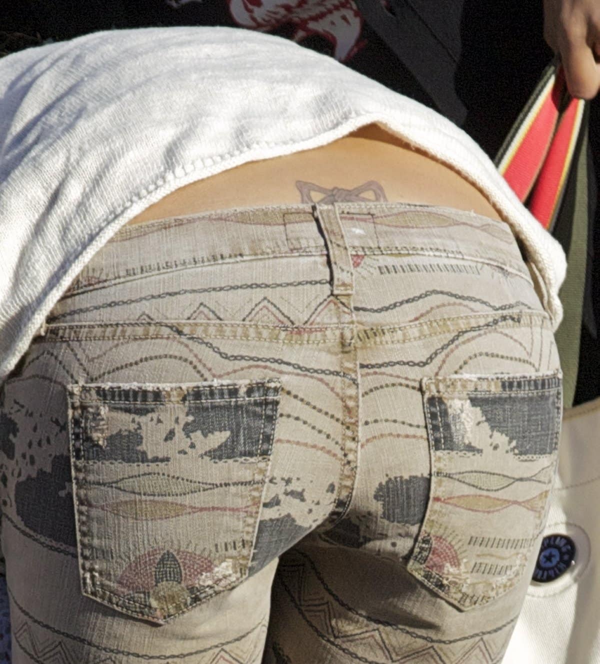 Jessica Alba reveals her small bow tattoo on her lower back, often referred to as a “tramp stamp,” a design she later admitted she regretted getting