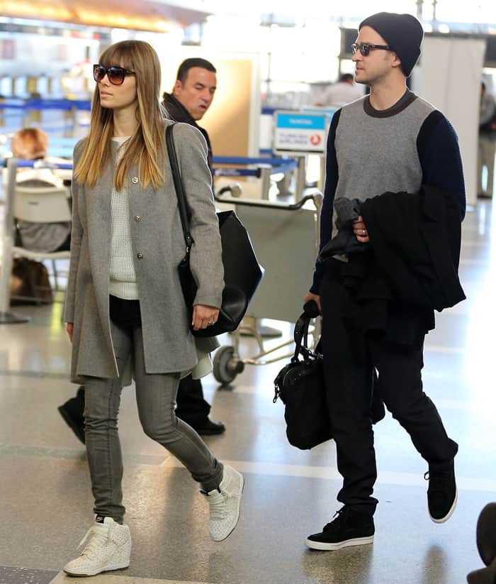 Jessica Biel kept it casual-chic in a gray coat, skinny jeans, and white woven wedge sneakers as she arrived at LAX with Justin Timberlake, who coordinated in black high-tops, joggers, and layered knits on February 16, 2013