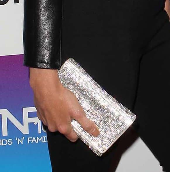 Jessica Sutta’s silver glitter clutch sparkles under the lights, echoing the glam energy of her sleek leather-and-mesh outfit