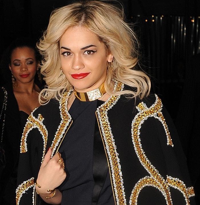 Rita Ora pairs voluminous blonde waves with bold red lips and a statement gold choker