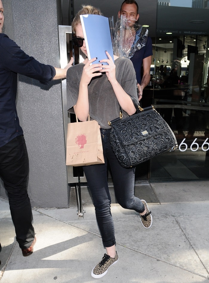 Ashley Benson wearing a casual chic ensemble that featured Dolce Gabbana's Miss Sicily Raffia Satchel, 7 For All Mankind skinny jeans, and Vans Authentic sneakers in leopard print