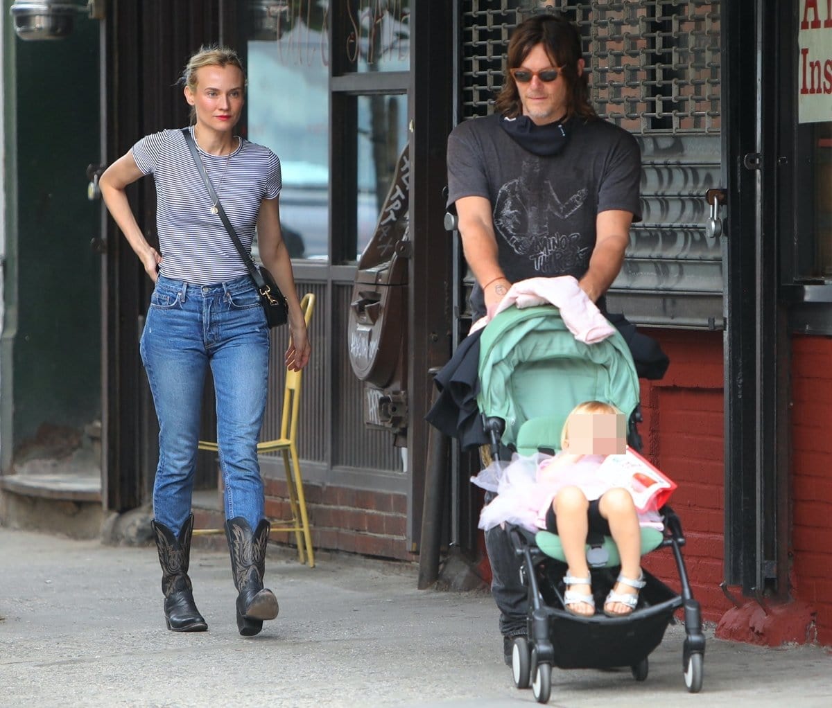 Diane Kruger steps out in New York City on June 1, 2021, pairing a fitted striped tee and high-waisted jeans with black leather Western boots, while Norman Reedus pushes their daughter in a stroller