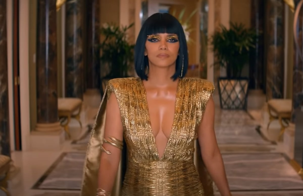 Halle Berry stuns as a modern Cleopatra in a plunging gold gown with dramatic shoulder pads and bold Egyptian-inspired makeup in Caesars Sportsbook's NFL Super Bowl commercial