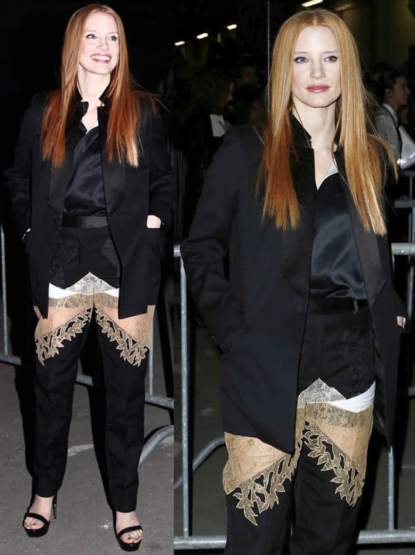 Jessica Chastain makes a striking entrance in Givenchy’s tailored black suit, elevated by intricate gold lace insets on the pants and classic black platform heels that balance edge with elegance